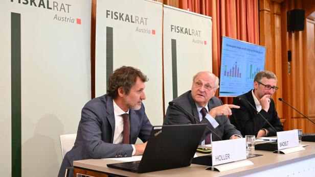 Die Vertreter des Fiskalrats, in der Mitte Präsident des Fiskalrates Christoph Badelt, sitzen nebeneinander bei der Pressekonferenz. Hinter ihnen sind drei Banner mit dem Fiskalrats-Logo.