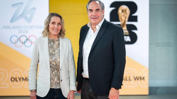 Veronika Dragon-Berger und Martin Szerencsi vor Logos für Milano Cortina 2026 und die FIFA Fussball-Weltmeisterschaft 2026.