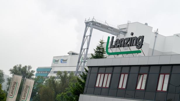 Das Lenzing-Logo prangt auf einem modernen Bürogebäude vor einem Fabrikkomplex.