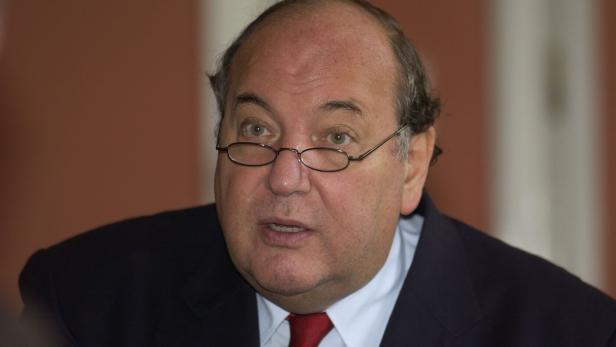 Ein Mann mit Brille, Anzug und roter Krawatte schaut aufmerksam.