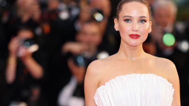 Jennifer Lawrence mit roten Lippen und hochgesteckten Haaren trägt ein weißes, trägerloses Kleid.