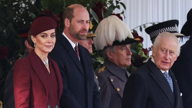 König Charles, Prinz William und Prinzessin Kate in Mänteln bei einer Veranstaltung.