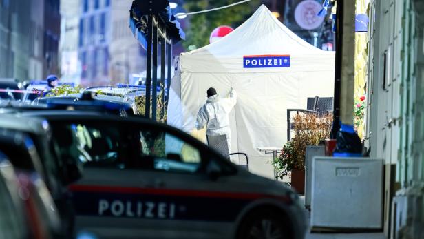 Ein Tatortzelt der Polizei steht auf der Straße, ein Beamter im Schutzanzug ist zu sehen.