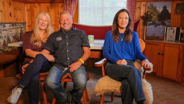 Kandidat Klaus (M.) sitzt mit seiner Bea (l.) und Kupplerin Nina Horowitz (r.) im Wohnzimmer.