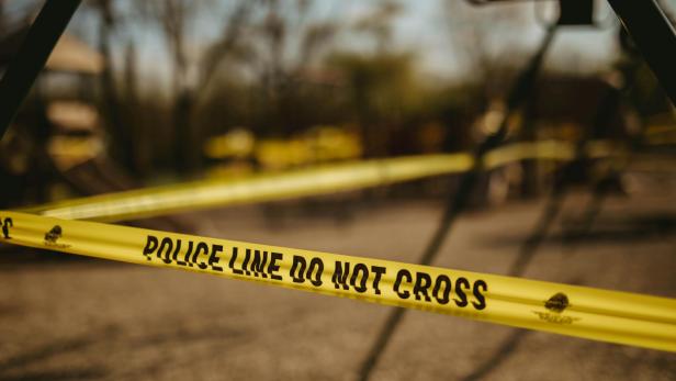 Gelbes Polizeiabsperrband zwischen Bäumen