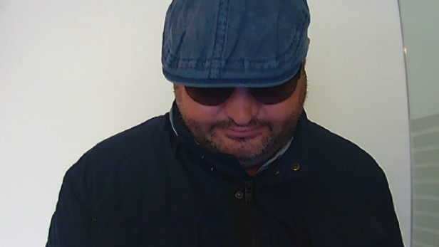 Eine Aufnahme von einer Bankomat-Kamera. Ein Mann mit blauer Kopfbedeckung und Sonnenbrille ist zu sehen.