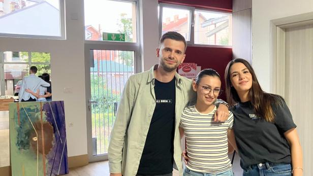 Drei junge Menschen stehen in der Mitte eines Raumes in ihrem Jugendzentrum.