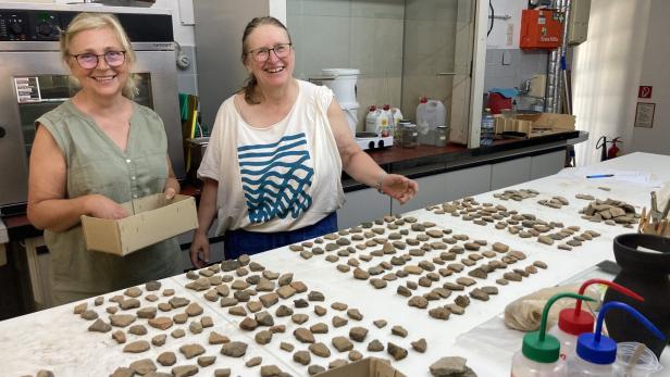 Zwei Frauen hinter Tisch voller Funde aus Stein