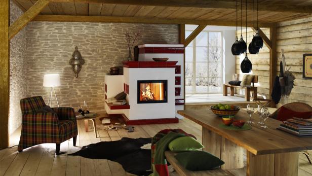 Gemütlicher Wohnraum in einem Holzhaus mit Kachelofen, gemauert und mit roten Kacheln. 