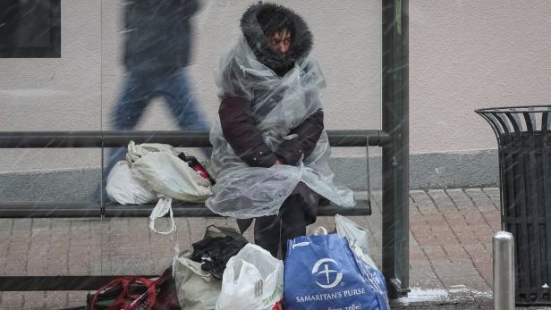 A homeless woman sits at a bus stop as she takes cover from the snow on a frosty winter morning in central Kyiv