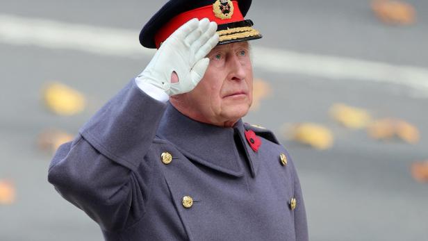 König Charles III. in Uniform und mit Hut salutiert.