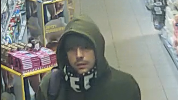 Mann mit grüner Jacke, Schal und Kapuze im Supermarkt