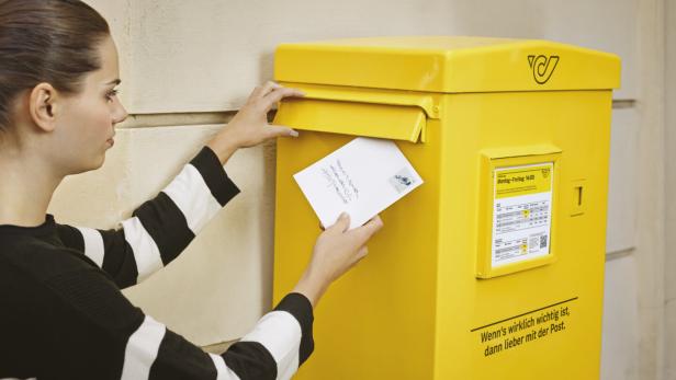 Eine Frau wirft einen Brief in einen Briefkasten