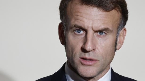 Nahaufnahme von Emmanuel Macron im Anzug vor hellem Hintergrund.