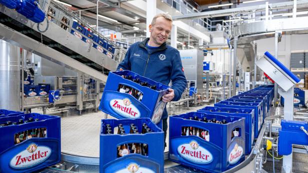 Arbeiter hebt Zwettler-Bierkiste von einem Förderband. DIe neue Abfüllanlage der Privatbrauerei Zwettl erstreckt sich über 3.000 Quadratmeter.