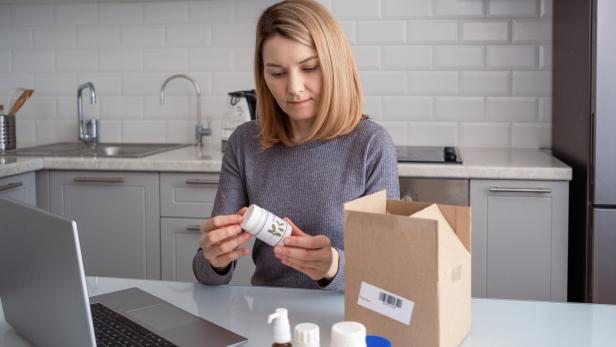 A woman opens a box with biologically active additives. Ordering food additives via the Internet.