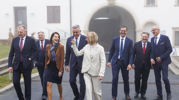 Mehrere Männer und Frauen gegen nebeneinander, im Hintergrund ein Schloss