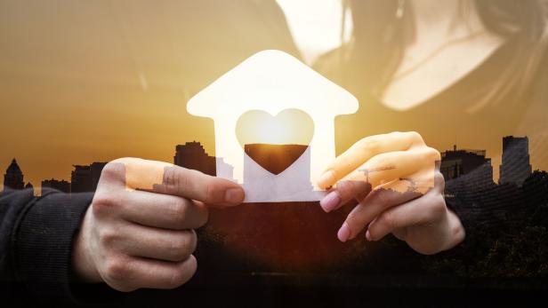 Paar hält das gemeinsame Haus in Händen.