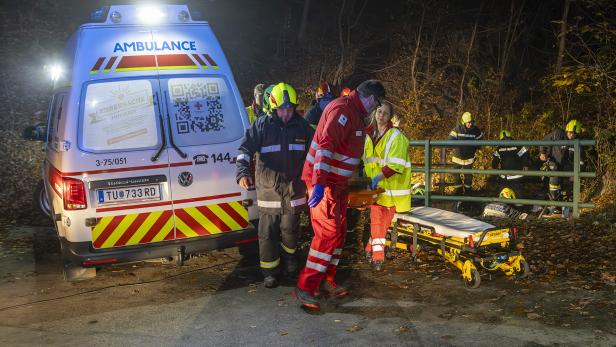 Eine Aufnahme von einem Rettungseinsatz bei Nacht. Neben dem Rettungsauto sind mehrere Menschen in unterschiedlichen Uniformen sowie eine Striker-Trage zu sehen.