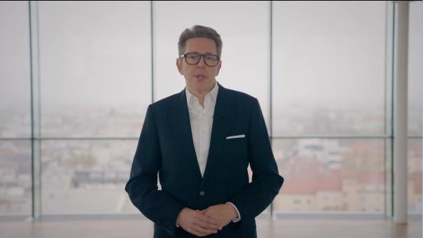 Mann steht vor Glasfassade, dahinter Wien