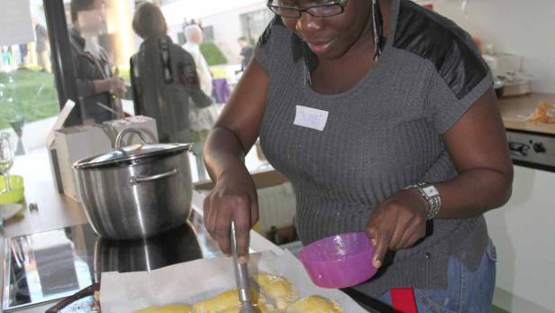 Eine Frau bestreicht Teigtaschen auf einem Backblech mit einer Flüssigkeit.