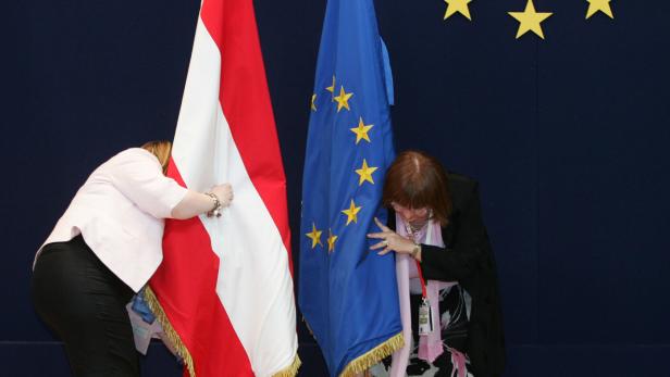 EU employees adjust Austrian and EU flags at the start of a EU heads of state summit in Brussels