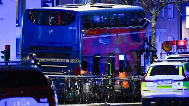 Ein blauer Bus steht neben Fahrrädern und einem Polizeiauto auf einer Straße.