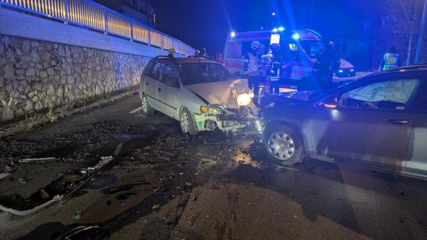 Zwei Autos sind frontal zusammengestoßen, Rettungskräfte und ein Krankenwagen sind vor Ort.