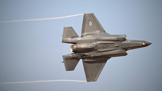 Ein grauer F-35-Kampfjet der US Air Force fliegt vor einem klaren Himmel und hinterlässt zwei Kondensstreifen.