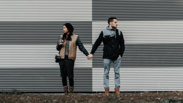 Paar hält sich an Händen, aber schaut in entgegengesetzte Richtung