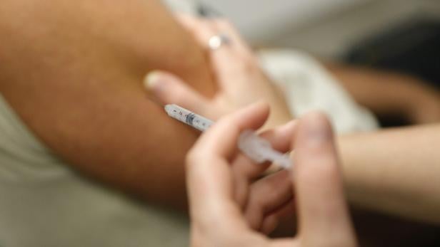 Eine Person erhält eine Injektion mit einer Spritze in den Oberarm.