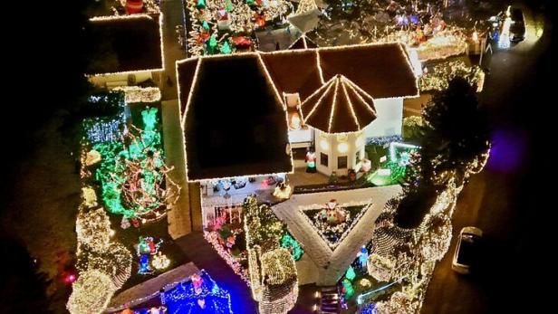 Ein Haus und Garten sind üppig mit bunten Weihnachtslichtern, Figuren und Dekorationen geschmückt.