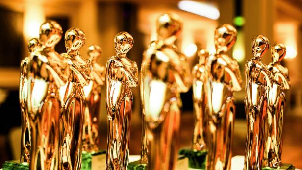 Mehrere goldene Romy-Statuetten stehen auf einem Tisch.