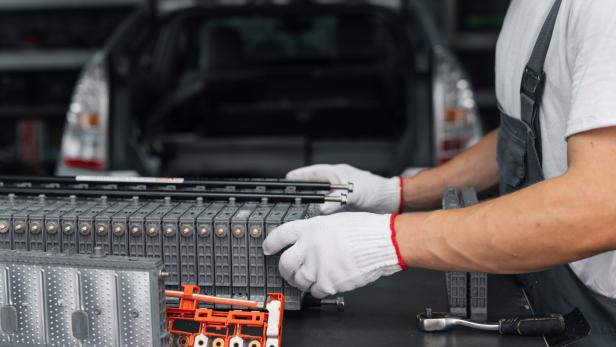 Serviceman repairs electric battery pack of hybrid car.