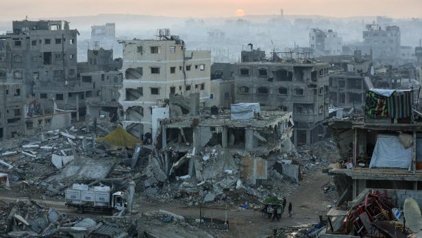 Die zerstörte Stadtlandschaft in Gaza zeigt Trümmer und beschädigte Gebäude unter einem blassen Himmel.