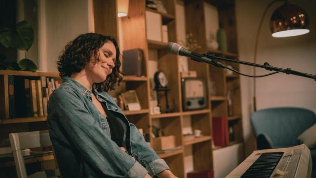 Die Sängerin Kathi Kallauch ist zu sehen, während sie Klavier spielt.
