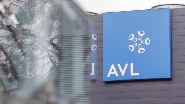 Ein blaues Schild mit dem AVL-Logo ist an einer grauen Fassade befestigt.