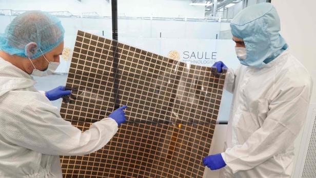 Zwei Personen in Schutzbekleidung mit Perowskit-Solarzellen in der Hand.