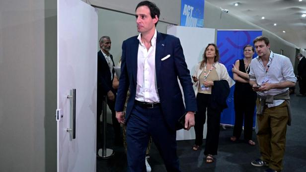 Wopke Hoekstra verlässt einen Raum, während andere Personen im Hintergrund stehen.