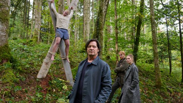Fritz Karl und Lisa Schützenberger stehen in der Krimi-Folge "Tod am See" vor einem Kreuz, auf dem ein Mann hängt