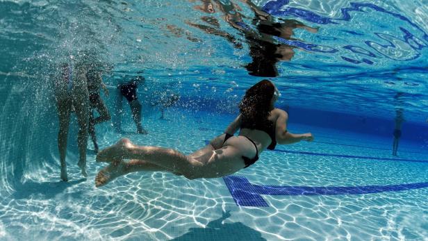 Ein Mädchen taucht unter dem Wasser - knapp über dem Grund.