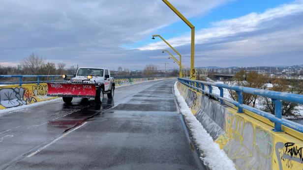 Räumfahrzeug fährt über die bereits geräumte "gelbe" Donaubrücke. 