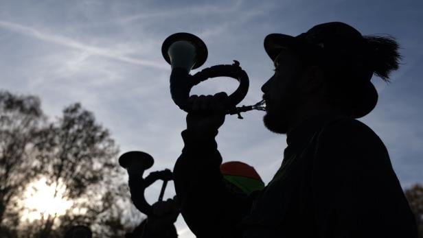Das Foto zeigt einen Jäger in sein Jagdhorn blasen.