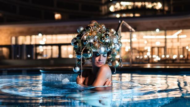 Eine Frau ist mit einer Lichterkette in einem Außenfreibad 