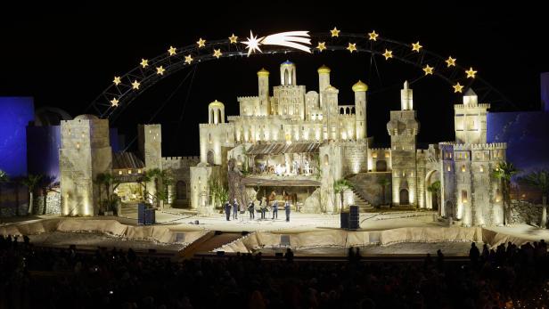 Bühnenbild mit hell beleuchteten, turmähnlichen Strukturen und einer Sternenbogen-Dekoration mit einem leuchtenden Kometen darüber.
