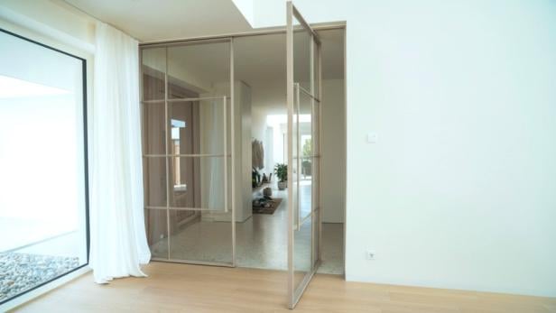 Ein heller Raum mit einer weißen Wand und einer großen Schiebetür aus Glas.