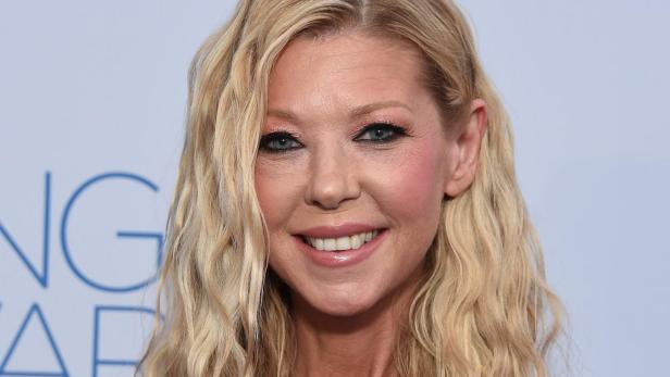 Tara Reid mit einem trägerlosen, farbenfrohen Kleid lächelt in die Kamera.