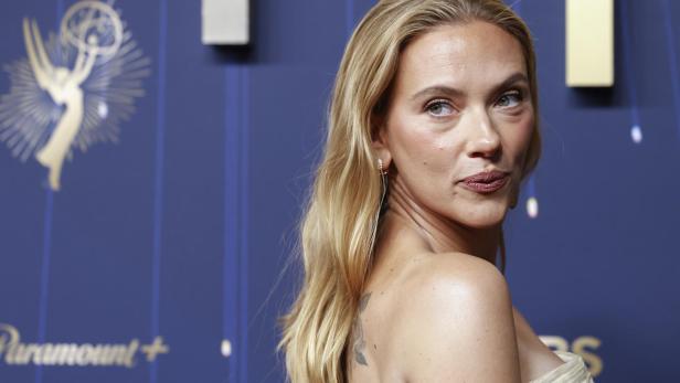 Scarlett Johansson blickt über ihre Schulter vor einem blauen Hintergrund.