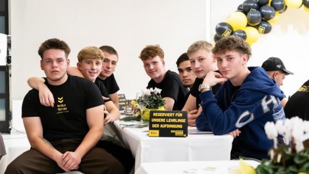 Mehrere Jugendliche sitzen an einem Tisch und schauen in die Kamera.