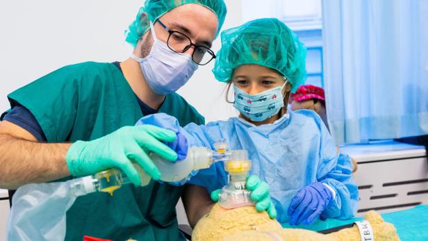 Ein Arzt und ein Kind verarzten einen Teddybär.